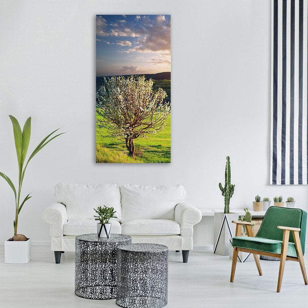 Tree in Mountain Meadow Vertical Canvas Wall Art in white, green and blue, single vertical panel hung on a wall