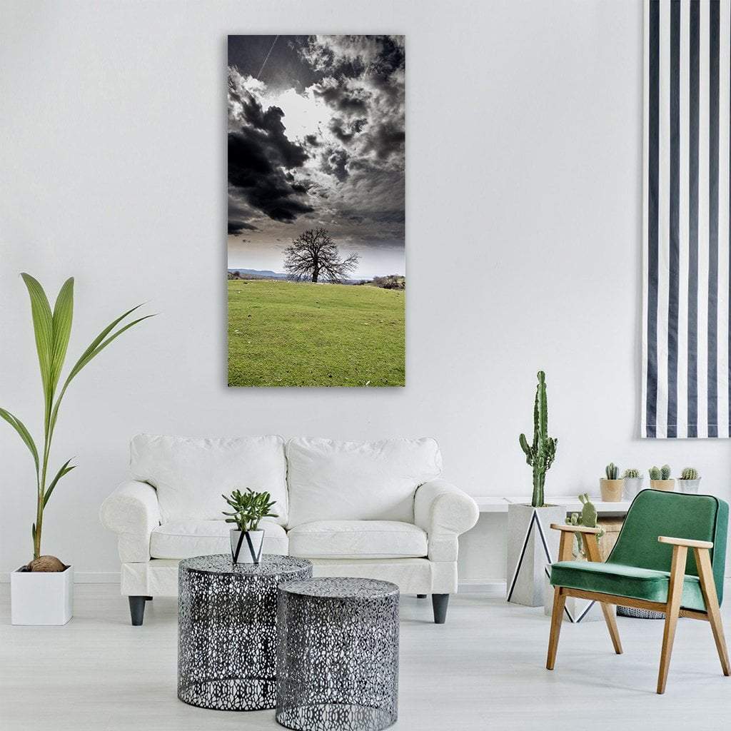 Tree Under Stormy Sky Vertical Canvas Wall Art in black, gray and green, single vertical panel hung on a wall