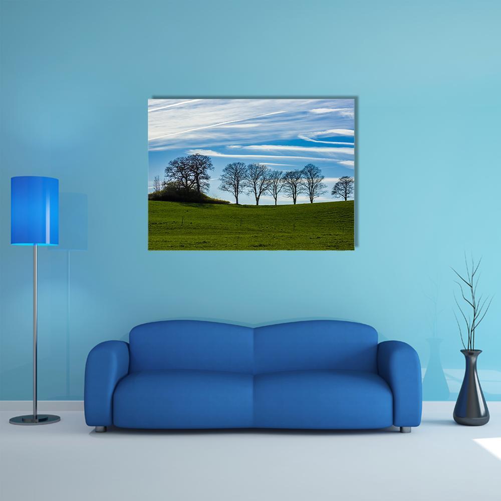 Bare Tree Silhouttes Against Blue Sky Canvas Wall Art in white, green and blue, single panel hung on a wall