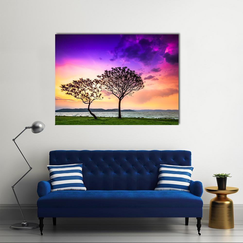 Sunset at Lake Balaton with Two Silhouetted Trees Canvas Wall Art in orange, yellow and purple, single panel hung on a wall