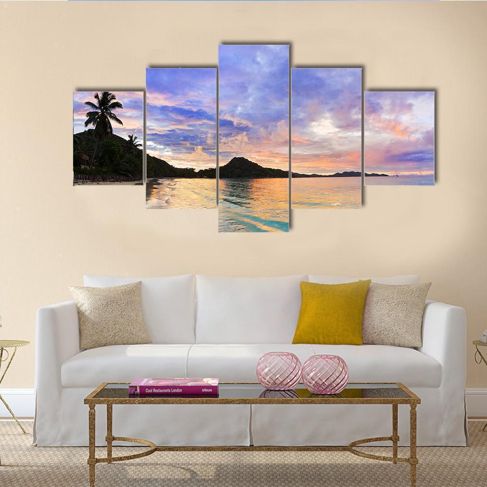 Tropical Beach Sunset with Palm Silhouette Canvas Wall Art in orange, blue and purple, 5 panel Star layout hung on a wall