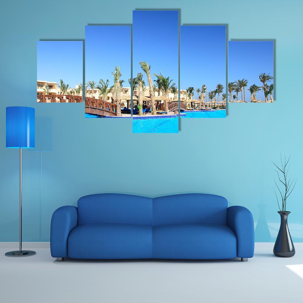 Tropical Park and Pool in Morocco Canvas Wall Art in beige and blue, 5 panel Star layout hung on a wall