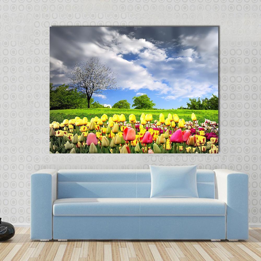 Tulip Field with Blossoming Tree Canvas Wall Art in yellow, green and blue, single panel hung on a wall