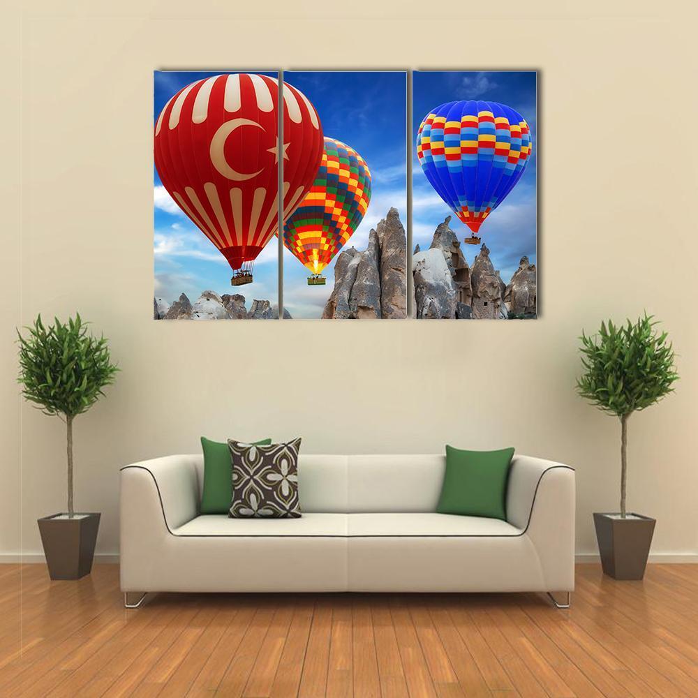 Hot Air Balloons Over Cappadocia Canvas Wall Art in beige, red and blue, 3 panel horizontal set hung on a wall