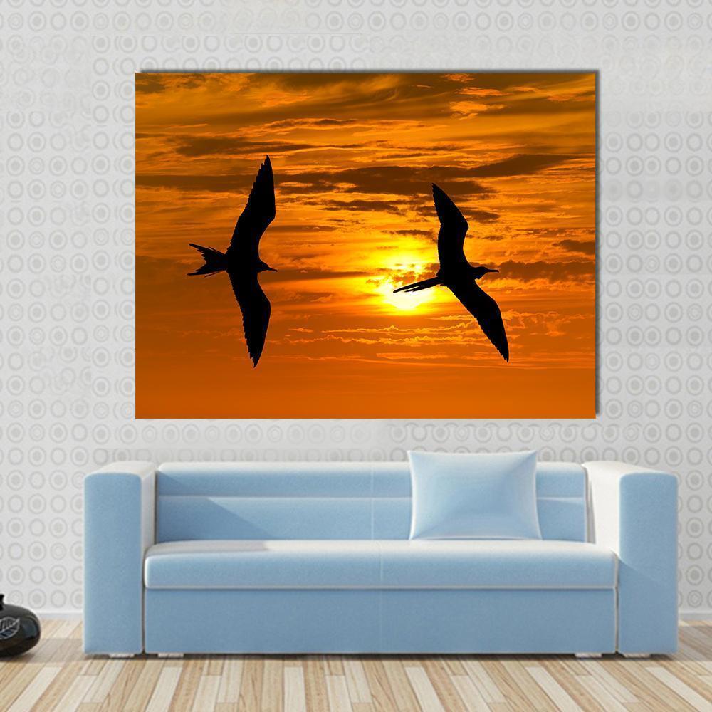 Two Birds Flying Silhouette at Sunset Canvas Wall Art in black, orange and yellow, single panel hung on a wall