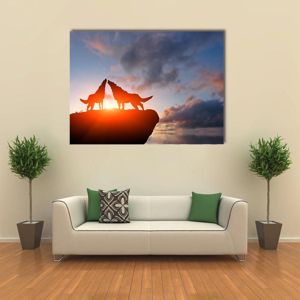 Two Wolves Howling on a Cliff at Sunset Canvas Wall Art in black, orange and blue, single panel hung on a wall