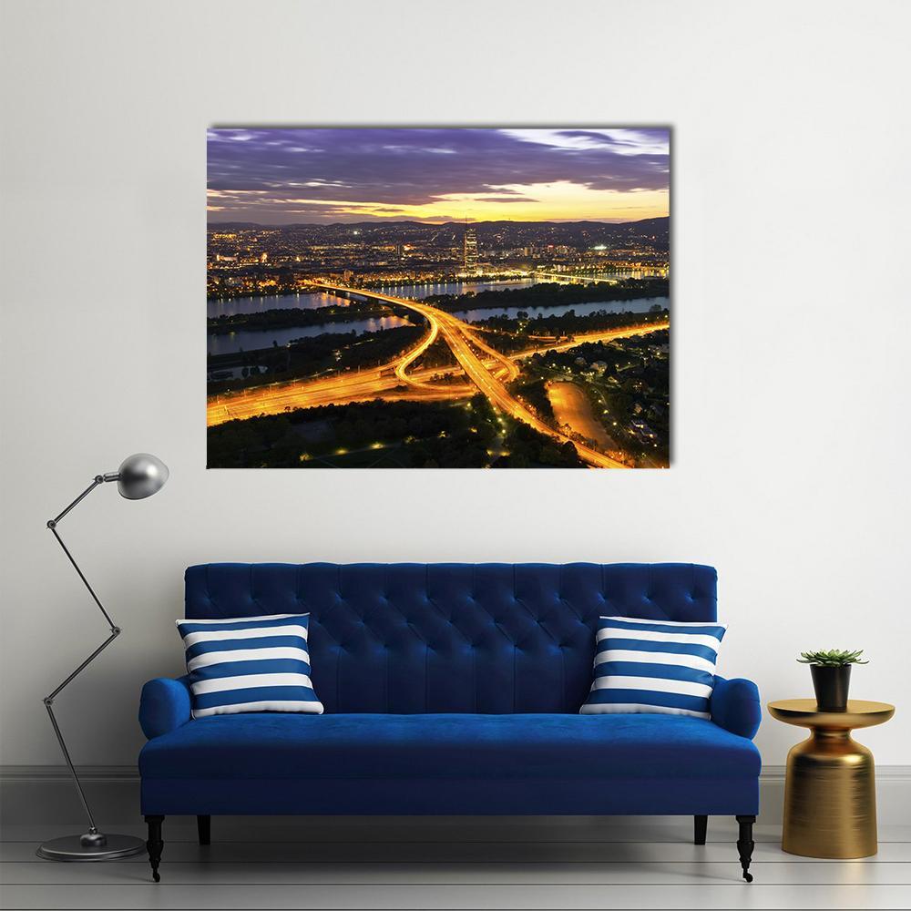 Dusk City Skyline with River Light Trails Canvas Wall Art in black, yellow and purple, single panel hung on a wall