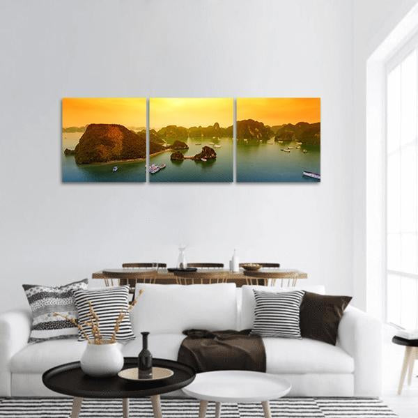 Halong Bay Sunset Over Limestone Karsts Panoramic Canvas Wall Art in orange, yellow and green, hung on a wall