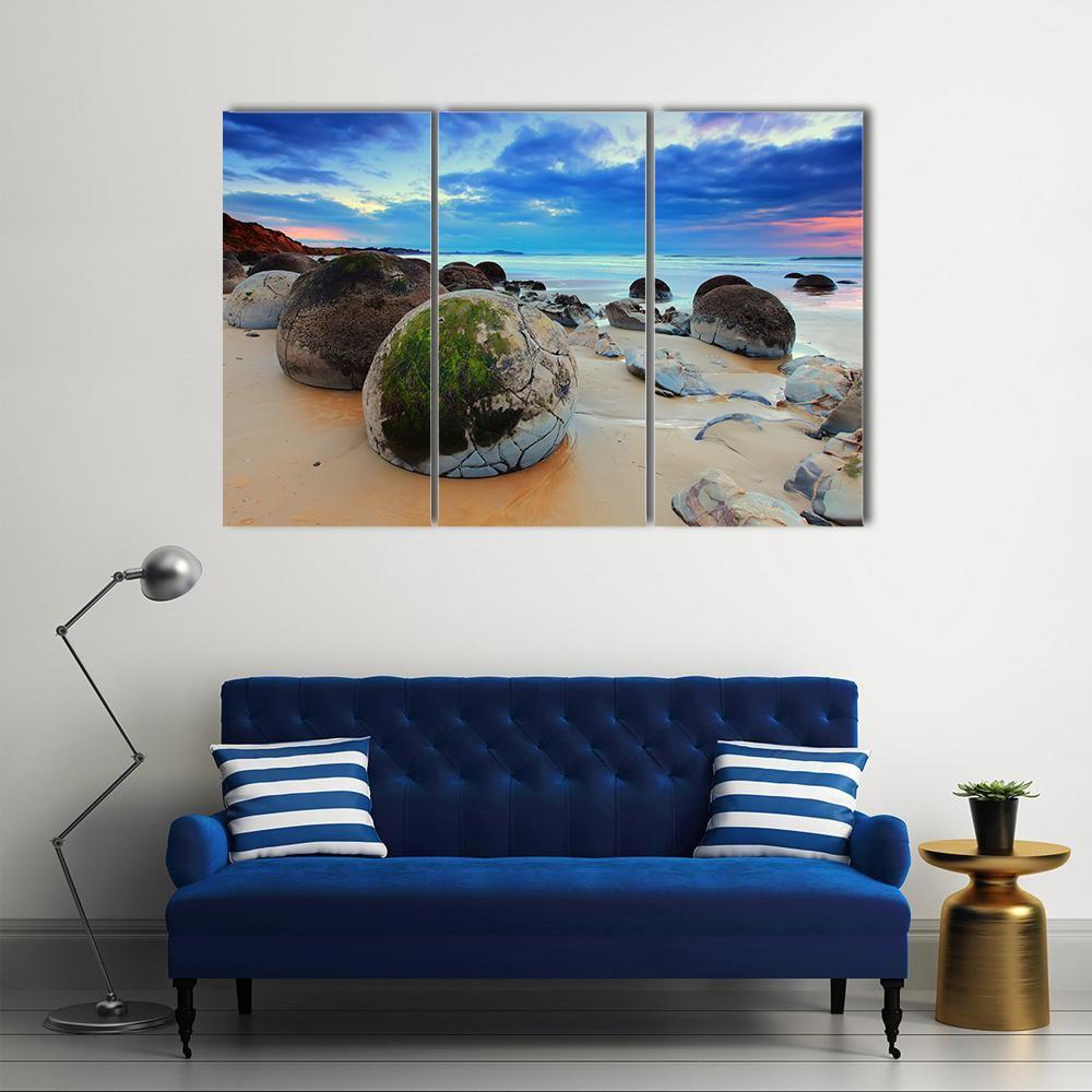 Moeraki Boulders at Sunset Canvas Wall Art in beige, brown and blue, 3 panel horizontal set hung on a wall