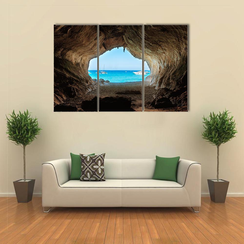 Cave View of Blue Sea and Sandy Beach Canvas Wall Art in beige, brown and blue, 3 panel horizontal set hung on a wall