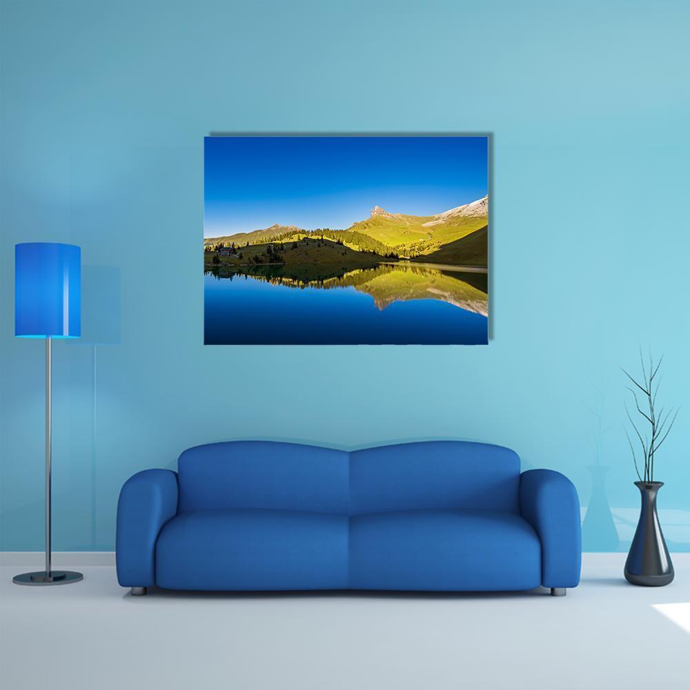 Forest and Mountains Reflected in Lake Canvas Wall Art in yellow, green and blue, single panel hung on a wall