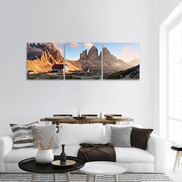 Dolomites Three Jagged Peaks at Sunrise Panoramic Canvas Wall Art in brown, orange and blue, hung on a wall