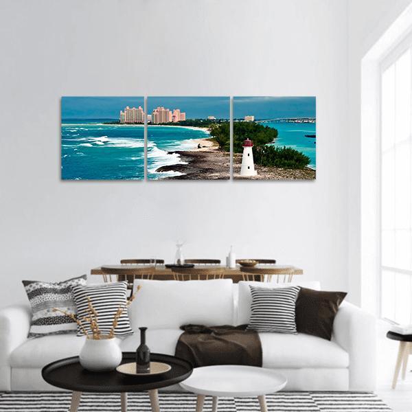 White Lighthouse on Tropical Shore Panoramic Canvas Wall Art in white, green and blue, hung on a wall