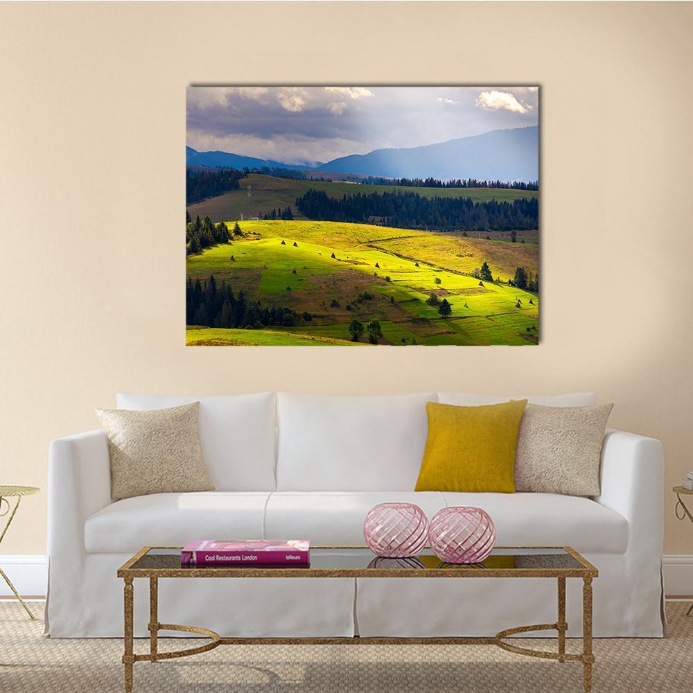 Sunlit Mountain Valley with Haystacks Canvas Wall Art in yellow, green and blue, single panel hung on a wall