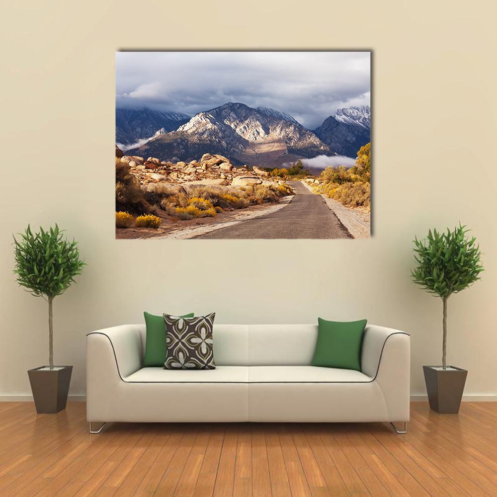 Curving Mountain Road to Snow-capped Peaks Canvas Wall Art in gray, brown and blue, single panel hung on a wall