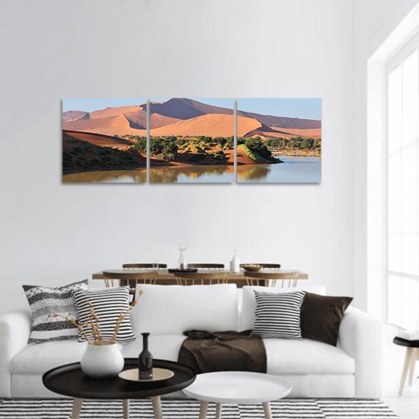 Flooded Desert Oasis with Reflective Lake Panoramic Canvas Wall Art in brown, orange and blue, hung on a wall