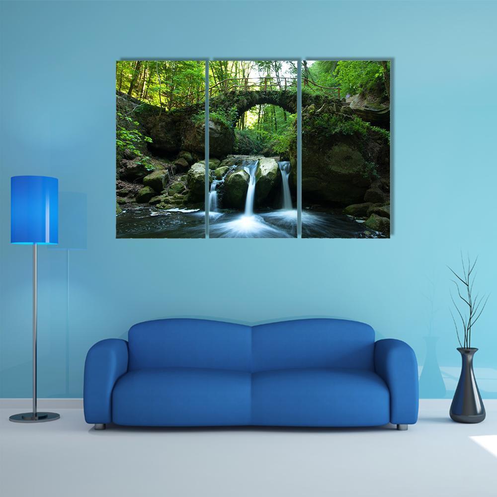 Moss-covered Stone Bridge and Waterfall Canvas Wall Art in gray, brown and green, 3 panel horizontal set hung on a wall