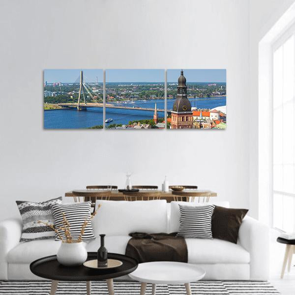 Riga River Skyline with Clock Tower Panoramic Canvas Wall Art in brown, green and blue, hung on a wall