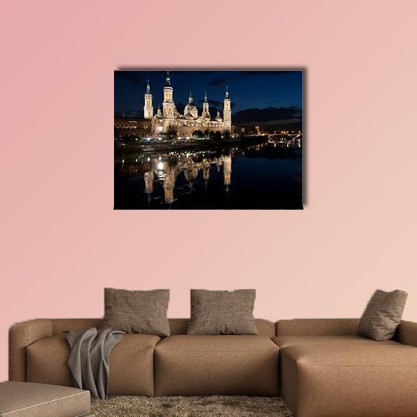 Our Lady of the Pillar Basilica at Night Canvas Wall Art in black, yellow and blue, single panel hung on a wall
