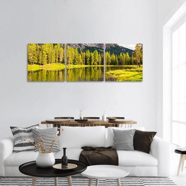 Mirror Lake with Evergreen Shoreline Panoramic Canvas Wall Art in yellow and green, hung on a wall