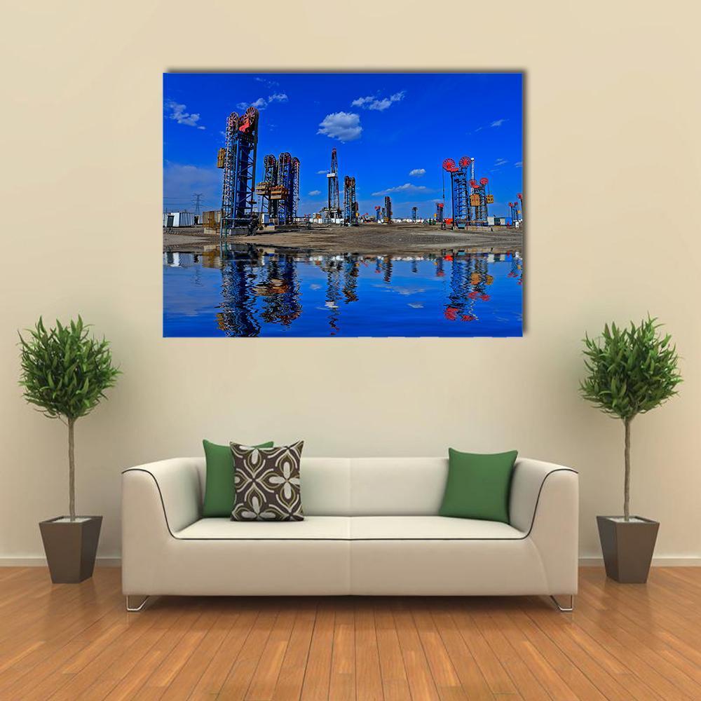Oil Pumpjacks Over Reflective Water Canvas Wall Art in black, orange and blue, single panel hung on a wall