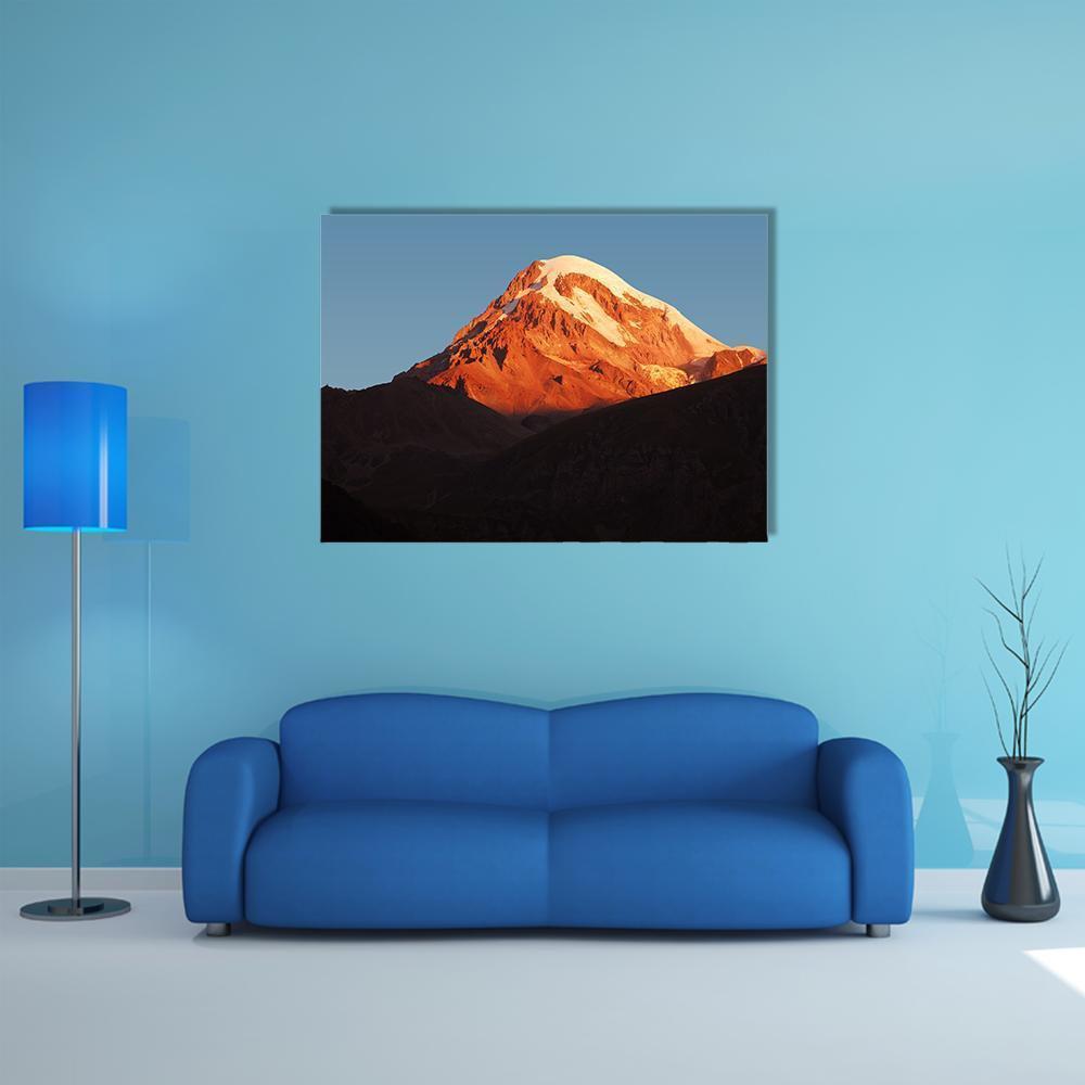 Kazbegi Volcano at Golden Hour Canvas Wall Art in black, orange and blue, single panel hung on a wall