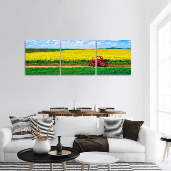 Vintage Red Tractor in Yellow Flower Field Panoramic Canvas Wall Art in yellow, green and blue, hung on a wall