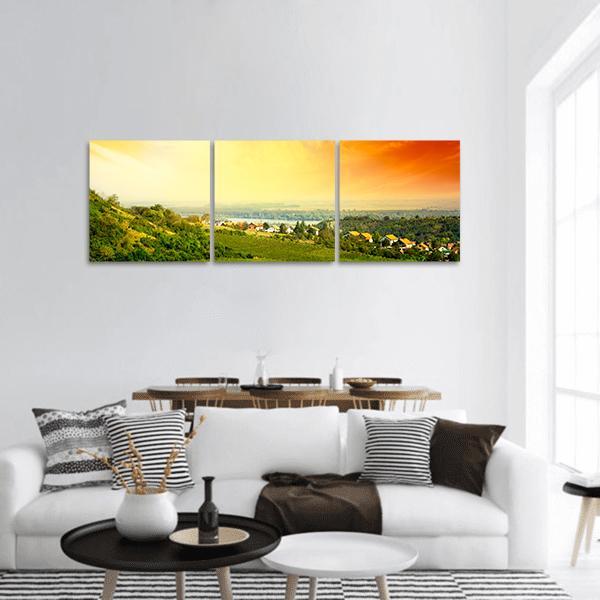 Sunset Over Vineyard and Rolling Hills Panoramic Canvas Wall Art in orange, yellow and green, hung on a wall