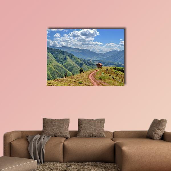 Winding Dirt Road to Small Wooden Hut Canvas Wall Art in brown, green and blue, single panel hung on a wall