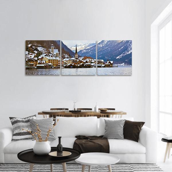 Snowy Lakeside Village with Church Spire Panoramic Canvas Wall Art in white, brown and blue, hung on a wall