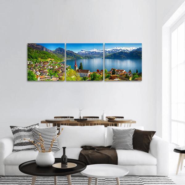 Lakeside Village with Red-spired Church Panoramic Canvas Wall Art in white, green and blue, hung on a wall