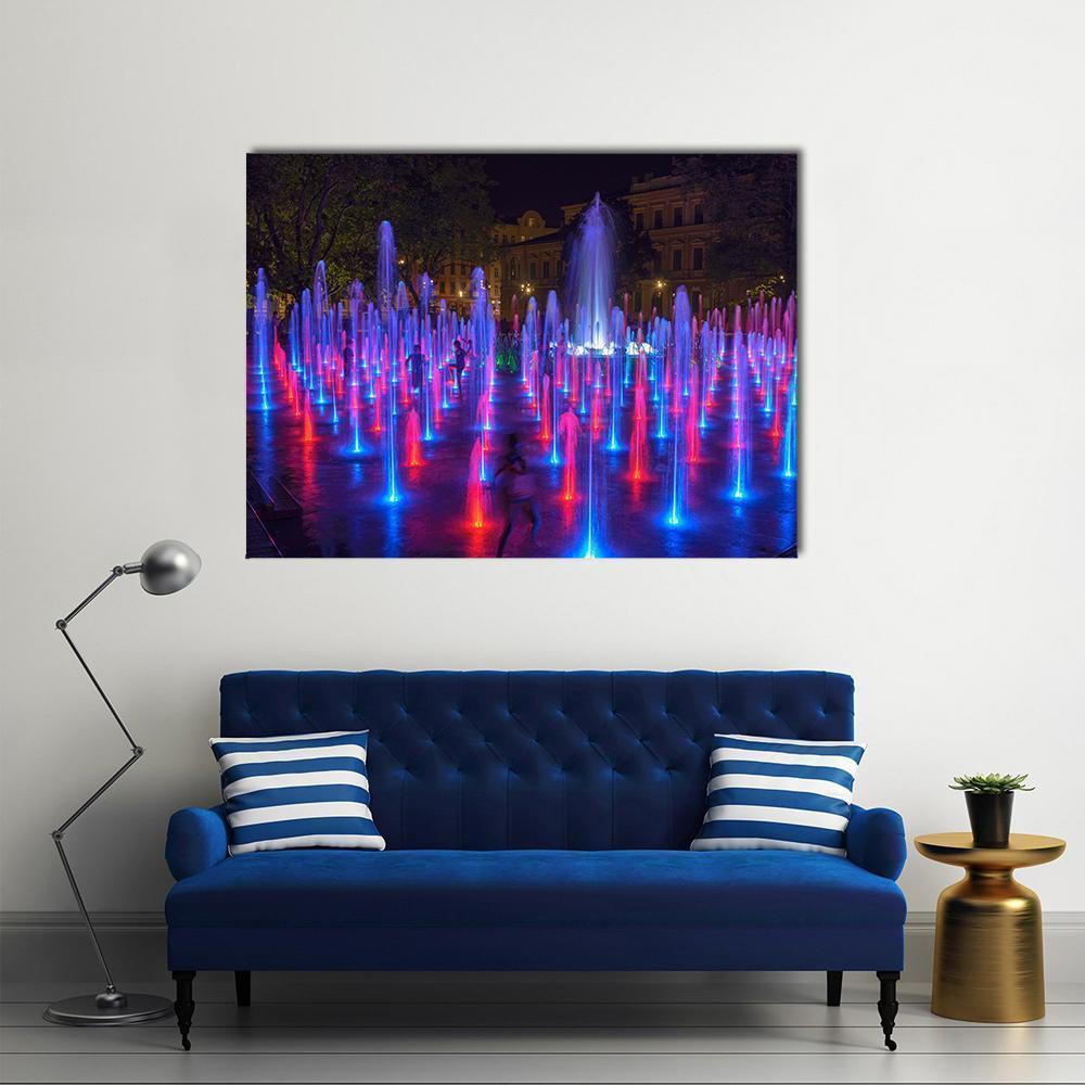 Vibrant Night City Fountain with Neon Jets Canvas Wall Art in blue, purple and pink, single panel hung on a wall