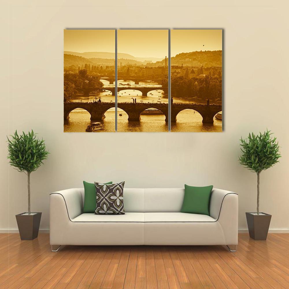 Vltava River in Prague Canvas Wall Art in brown, gold and yellow, 3 panel horizontal set hung on a wall