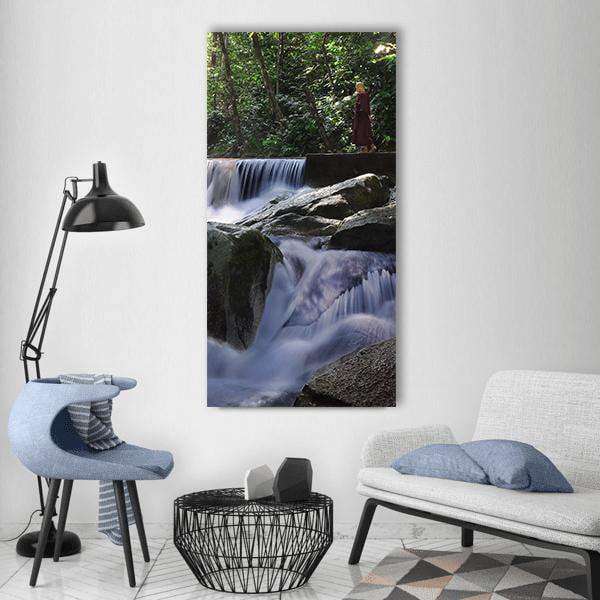 Monk in Red Robe Above Waterfall Vertical Canvas Wall Art in white, gray and green, single vertical panel hung on a wall