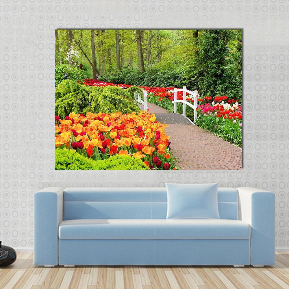 Walkway Through Spring Flowers at Keukenhof Gardens Canvas Wall Art in red, orange and green, single panel hung on a wall