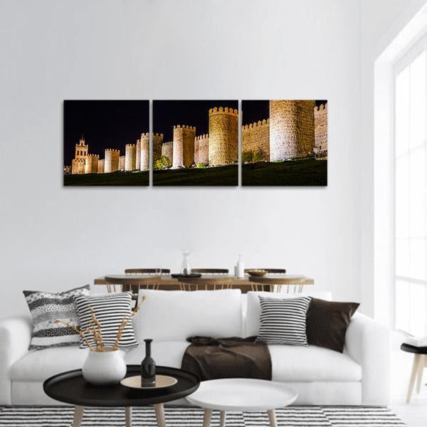 Walls of Avila at Night Panoramic Canvas Wall Art in black, brown and yellow, hung on a wall