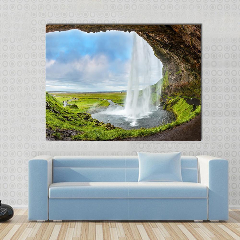 Waterfall Above the Cave Canvas Wall Art in brown, green and blue, single panel hung on a wall