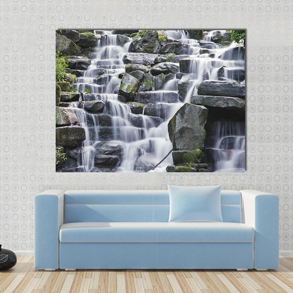 Cascading Water Over Moss-covered Rocks Canvas Wall Art in white, gray and green, single panel hung on a wall