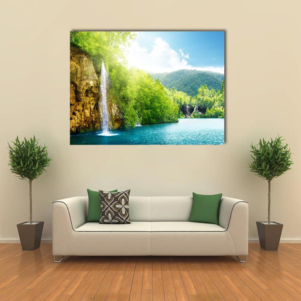 Waterfalls Over Pristine Blue Lake Canvas Wall Art in yellow, green and blue, single panel hung on a wall