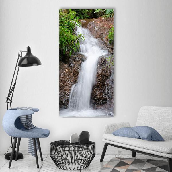 Portugal Waterfall Among Green Foliage Vertical Canvas Wall Art in white, brown and green, single vertical panel hung on a wall