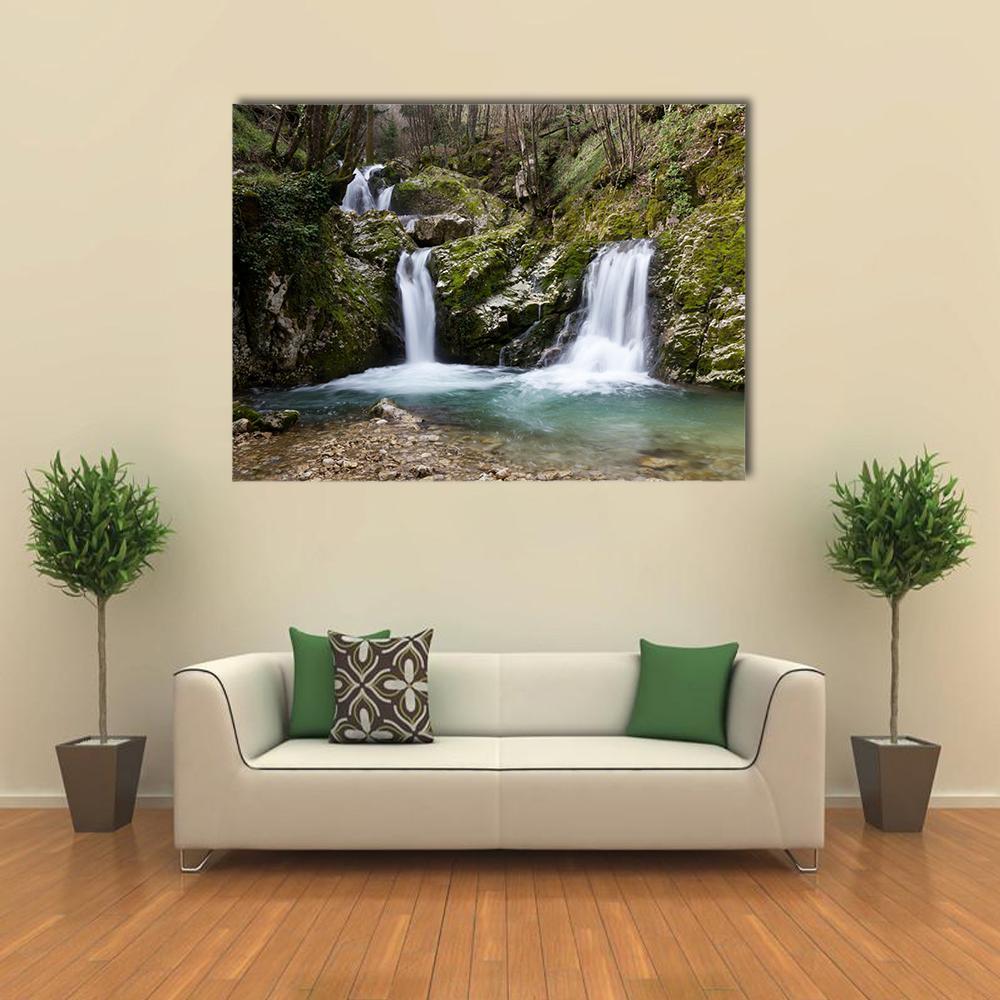 Moss-covered Multi-tier Waterfall with Turquoise Pool Canvas Wall Art in brown, green and blue, single panel hung on a wall