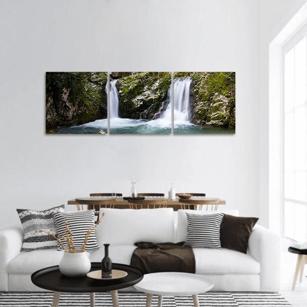 Twin Waterfalls Over Mossy Cliffs Panoramic Canvas Wall Art in black, white and green, hung on a wall