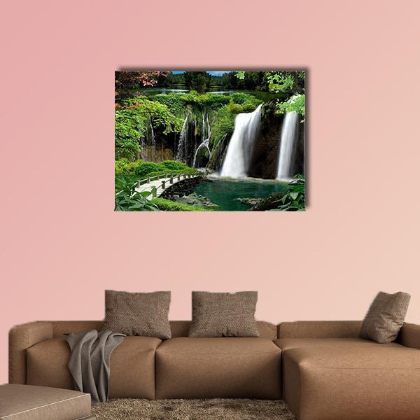 Cascading Waterfalls with Wooden Footbridge and Pink Blossoms Canvas Wall Art in white, brown and green, single panel hung on a wall