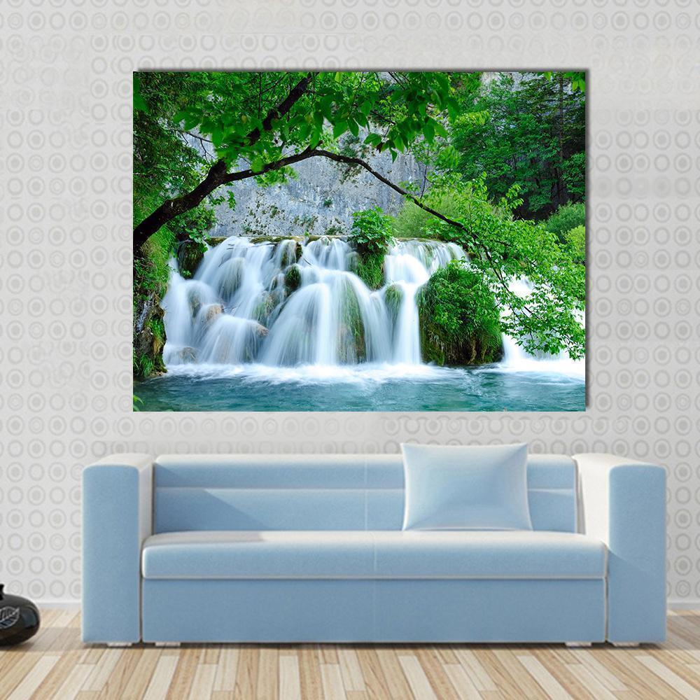 Cascading Waterfall Over Mossy Rocks Canvas Wall Art in white, green and blue, single panel hung on a wall