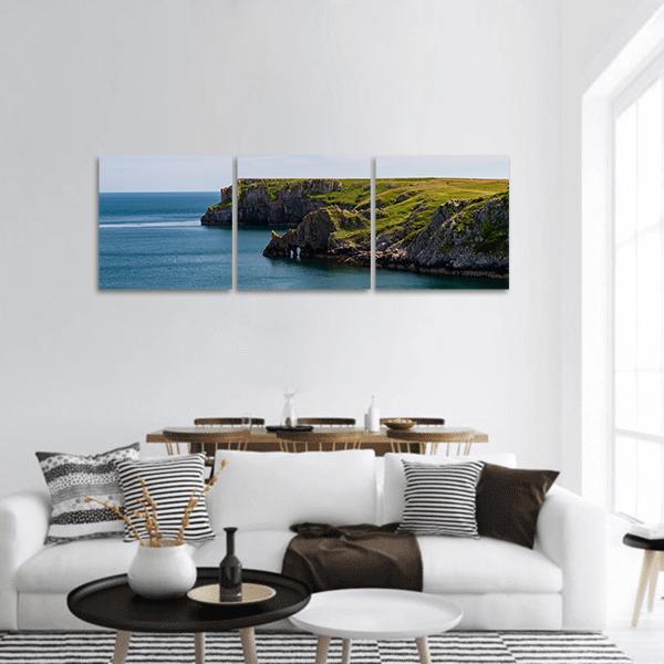 Welsh Coastal Cliffs Over Calm Sea Panoramic Canvas Wall Art in green and blue, hung on a wall