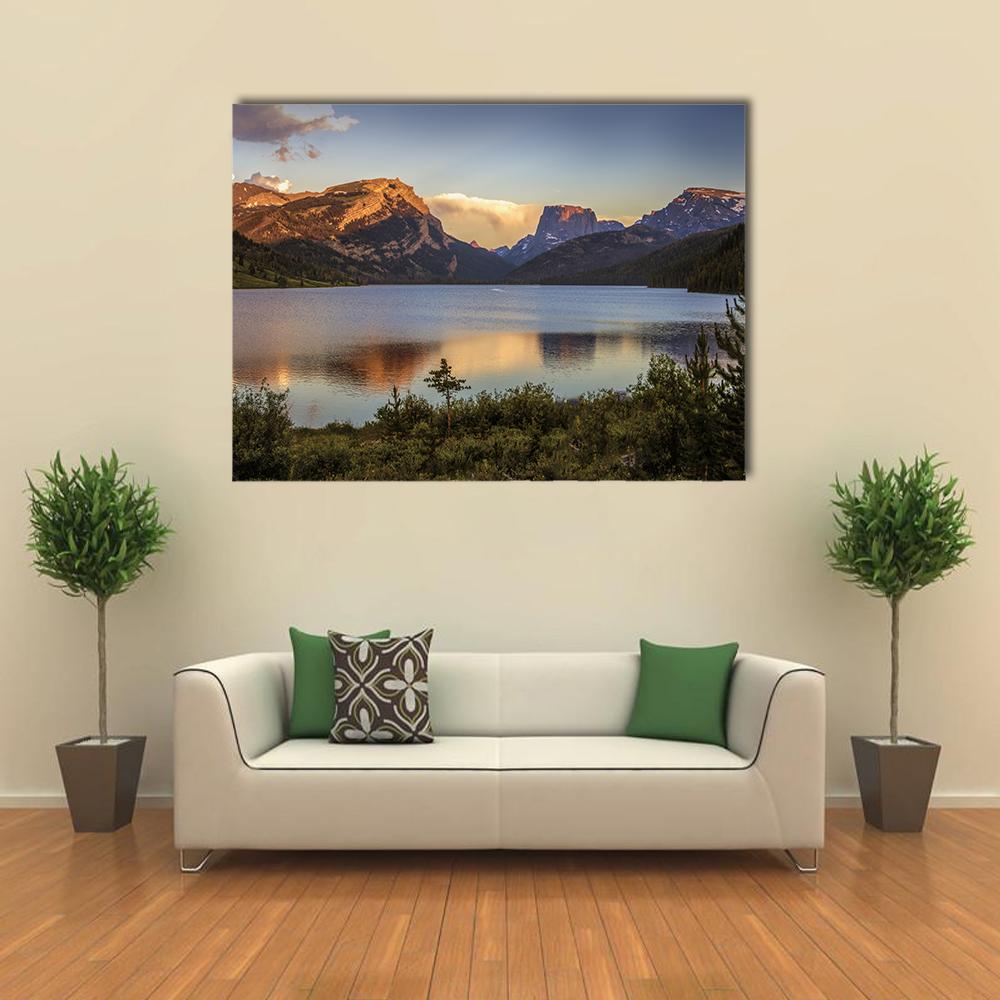 Sunlit Mountain Range Over Calm Lake Canvas Wall Art in brown, yellow and blue, single panel hung on a wall