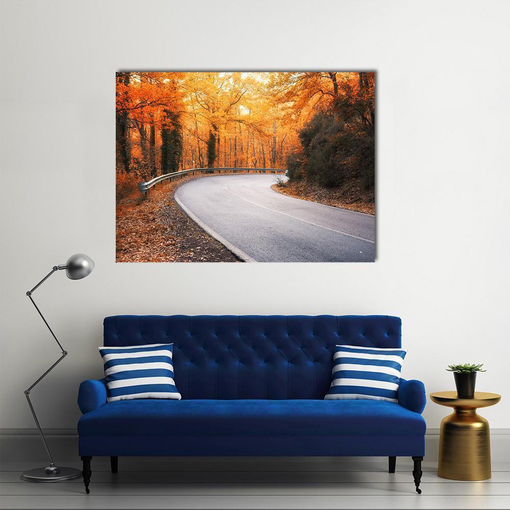 Winding Road Through Autumn Trees Canvas Wall Art in gray, orange and yellow, single panel hung on a wall