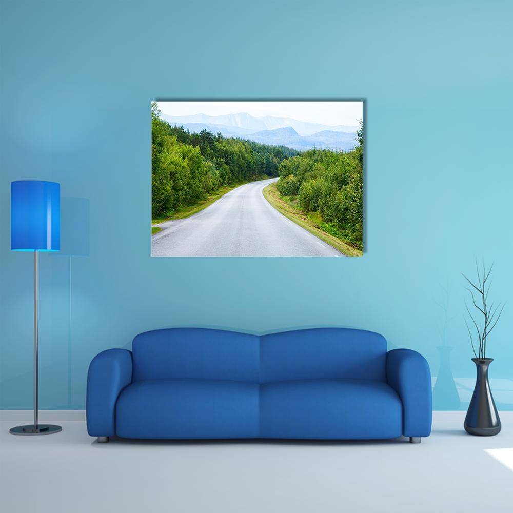 Winding Road Through Green Forest Canvas Wall Art in gray, green and blue, single panel hung on a wall