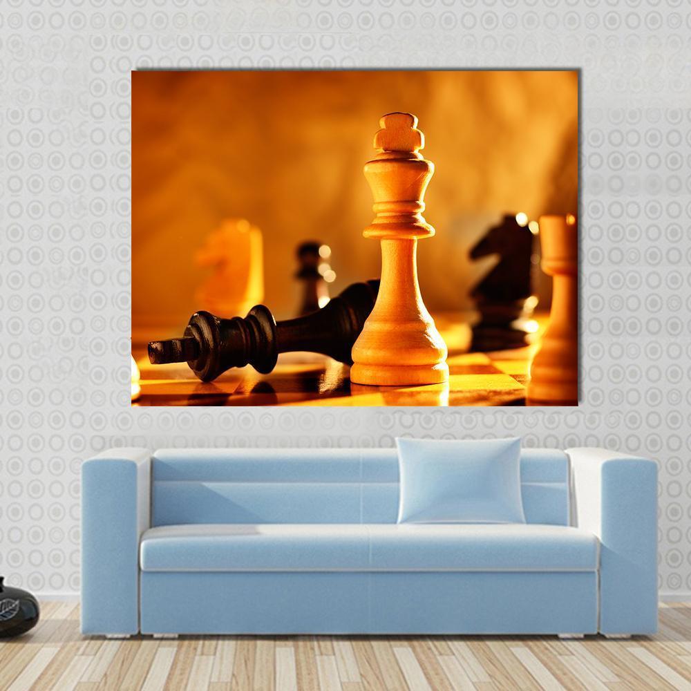 Standing Chess King Beside Fallen Opponent Canvas Wall Art in black, gold and yellow, single panel hung on a wall