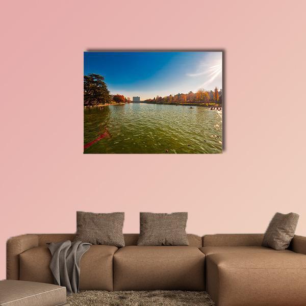Winter Sun Over City Lake Canvas Wall Art in yellow, green and blue, single panel hung on a wall